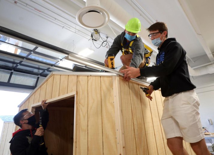 Three students building a shed