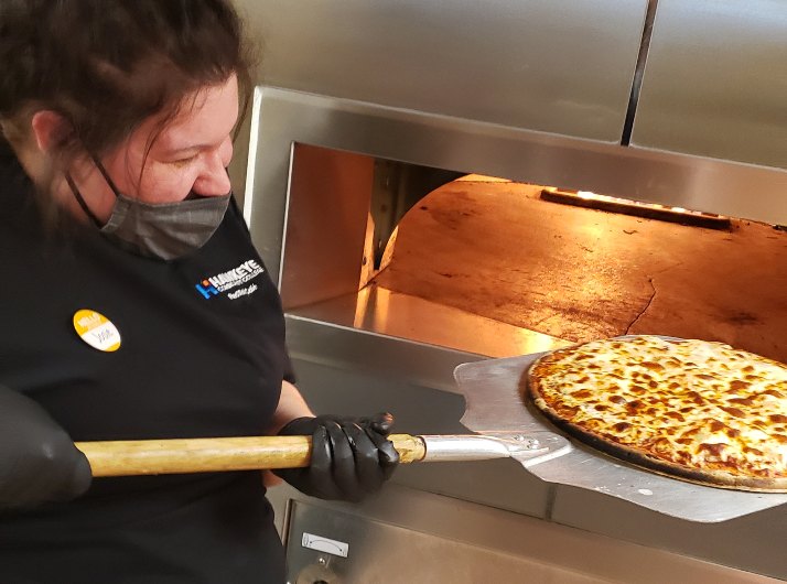 A student at the RedTail Cafe prepares pizza